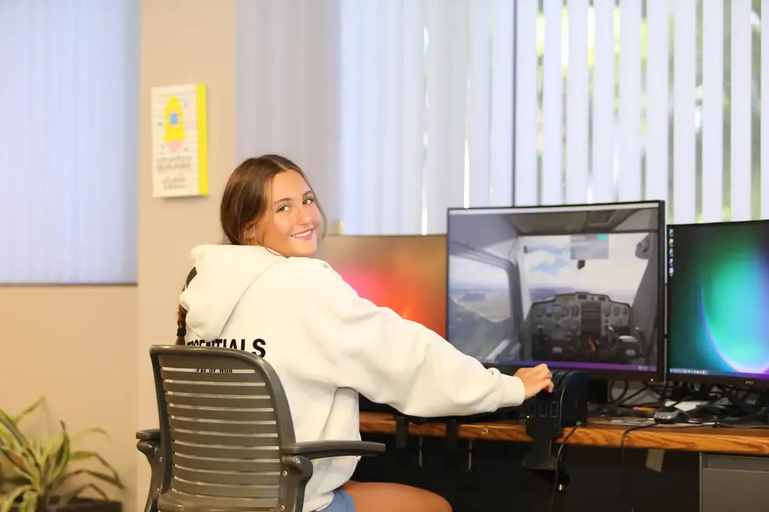 A Freedom student smiling at the flight simulator