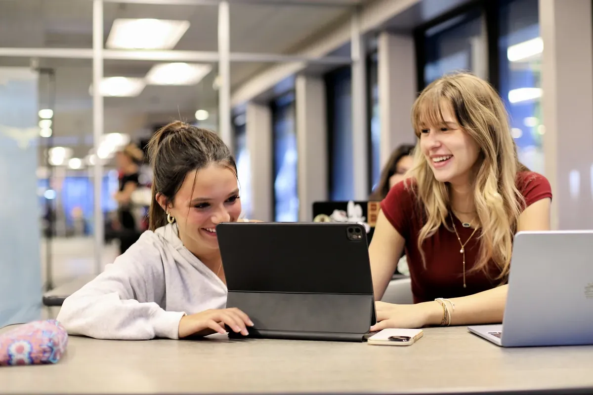 Two Freedom students learning together on a tablet and laptop
